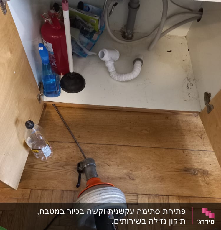 כלי עבודה של אינסטלטור מתחת לכיור במטבח